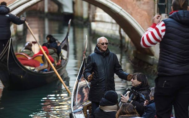 Gondola ride with musician playing accordion on Venice canal.
