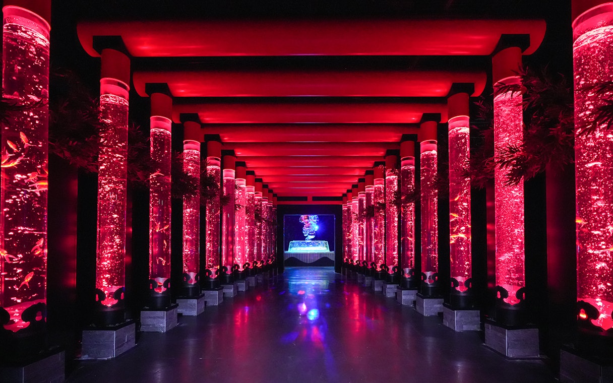 Illuminated red walkway with fish tanks at Art Aquarium Ginza.
