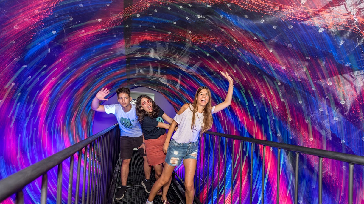 Visitors in a colorful vortex tunnel at Museum of Illusions Thessaloniki.