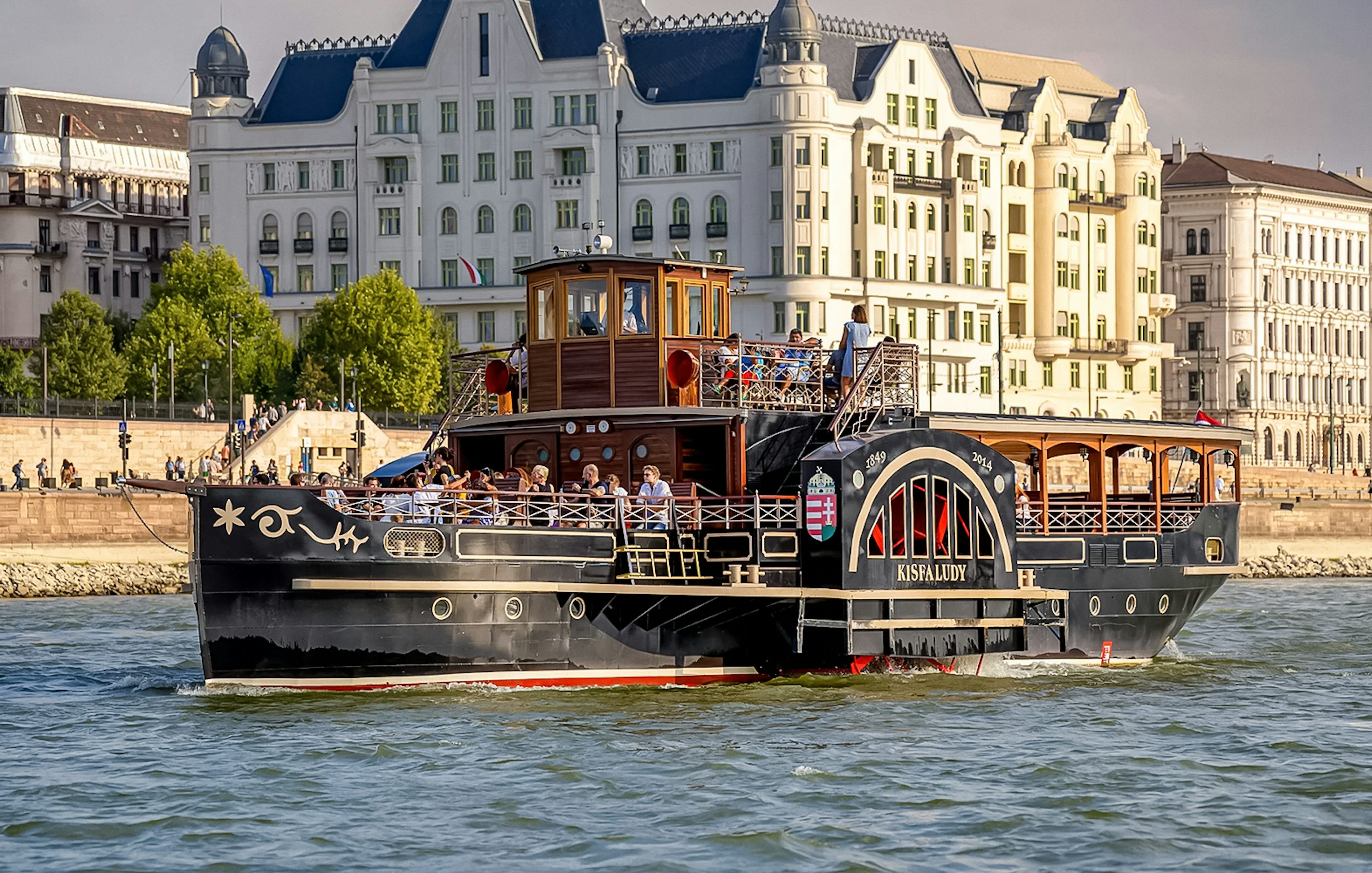 Historic cruise ship on the Danube River in Budapest with passengers enjoying the view.