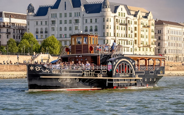 Historic cruise ship on the Danube River in Budapest with passengers enjoying the view.
