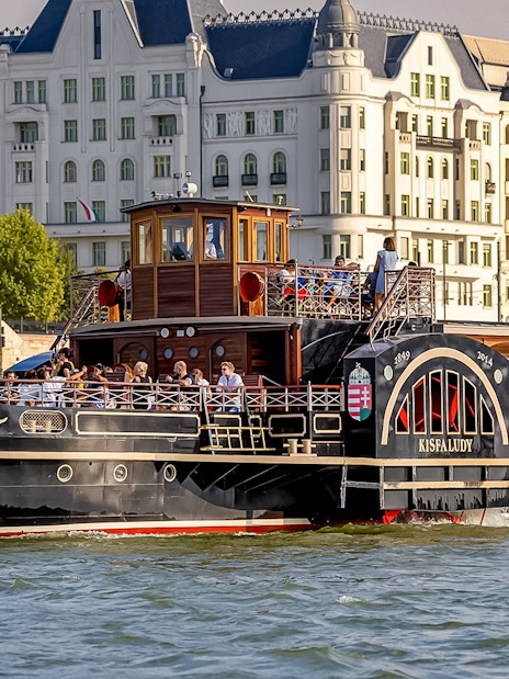 Historic cruise ship on the Danube River in Budapest with passengers enjoying the view.