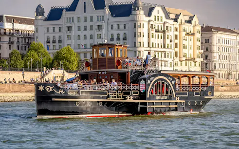 Historic cruise ship on the Danube River in Budapest with passengers enjoying the view.