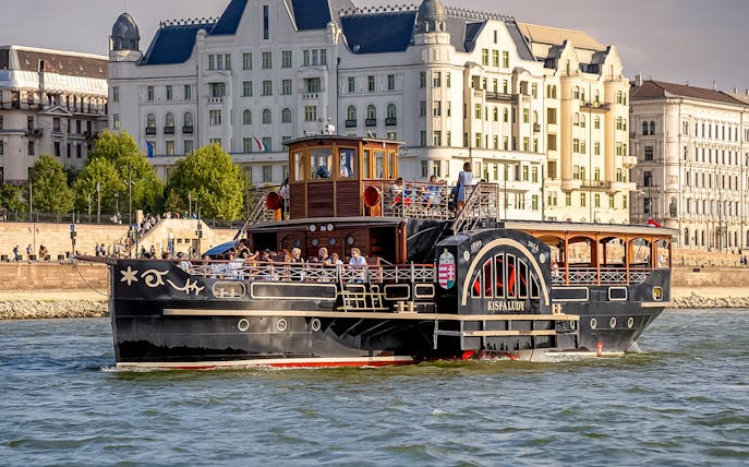Historic cruise ship on the Danube River in Budapest with passengers enjoying the view.