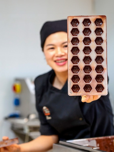 Chocolatier holding a tray of chocolate molds at Choco Story Brussels.