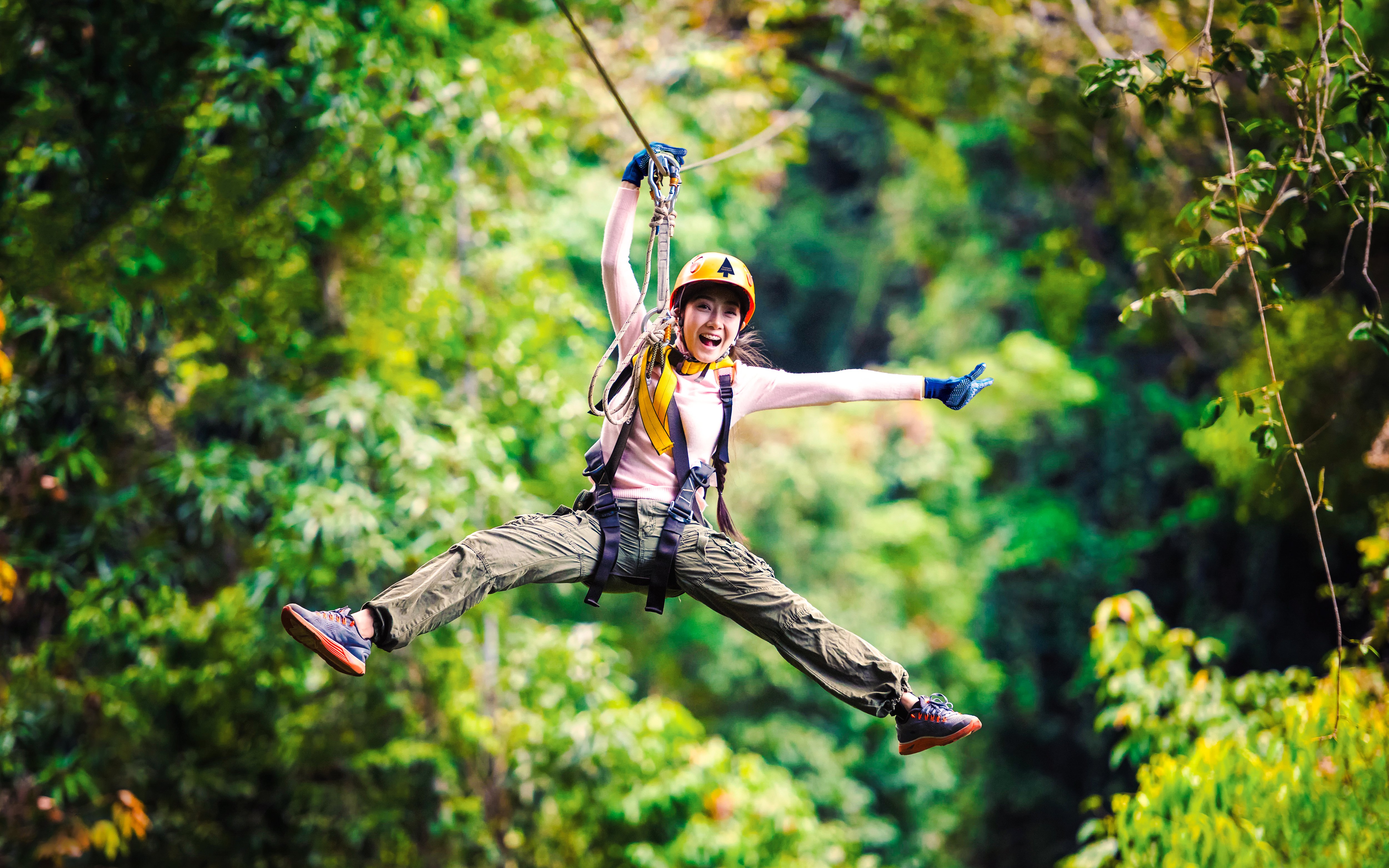 Person ziplining through Daintree Rainforest, surrounded by lush greenery.