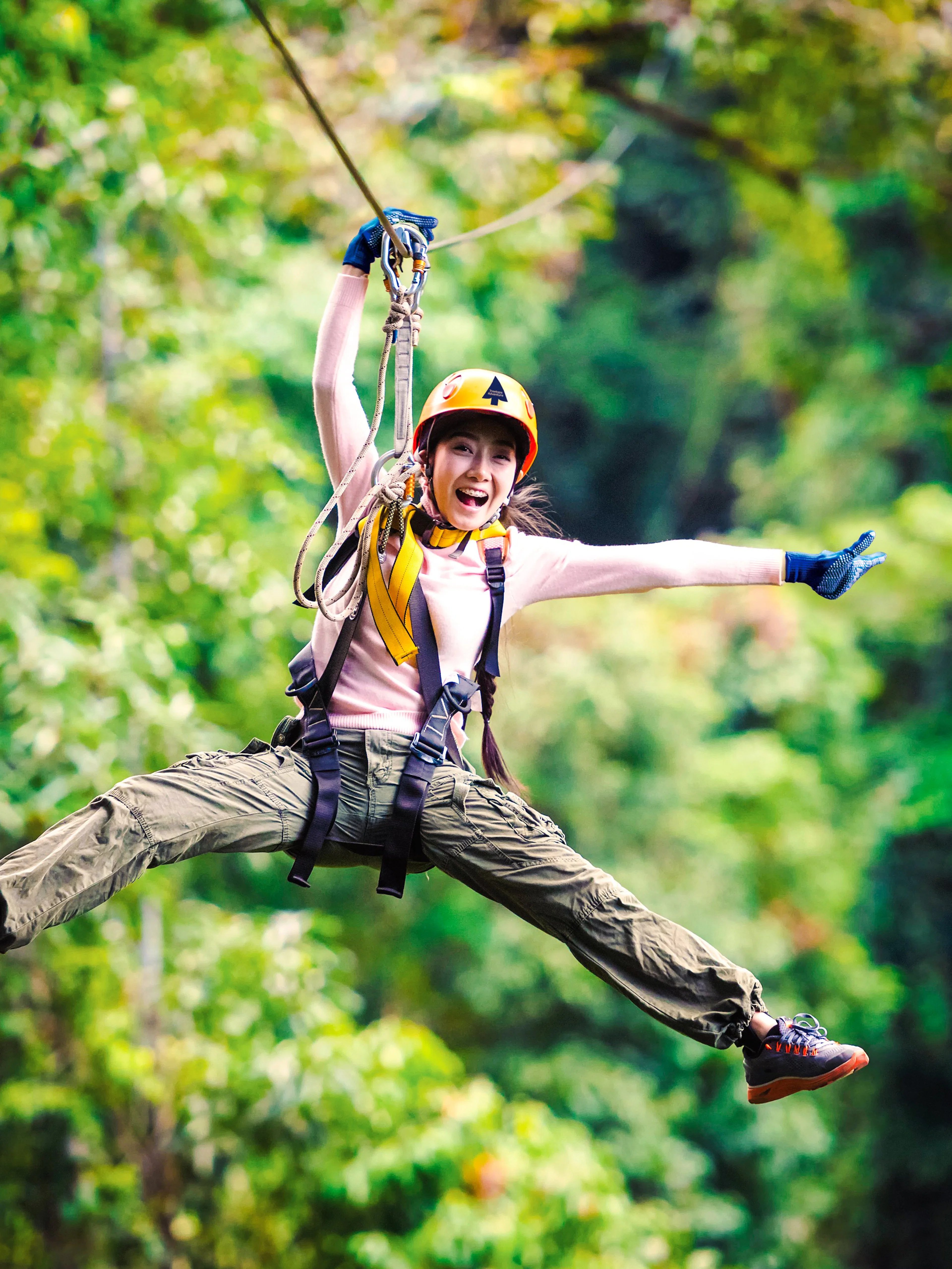 Person ziplining through Daintree Rainforest, surrounded by lush greenery.