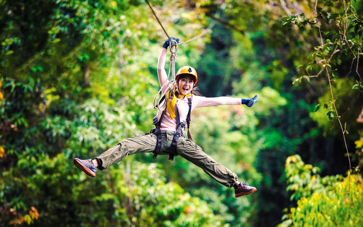 Person ziplining through Daintree Rainforest, surrounded by lush greenery.