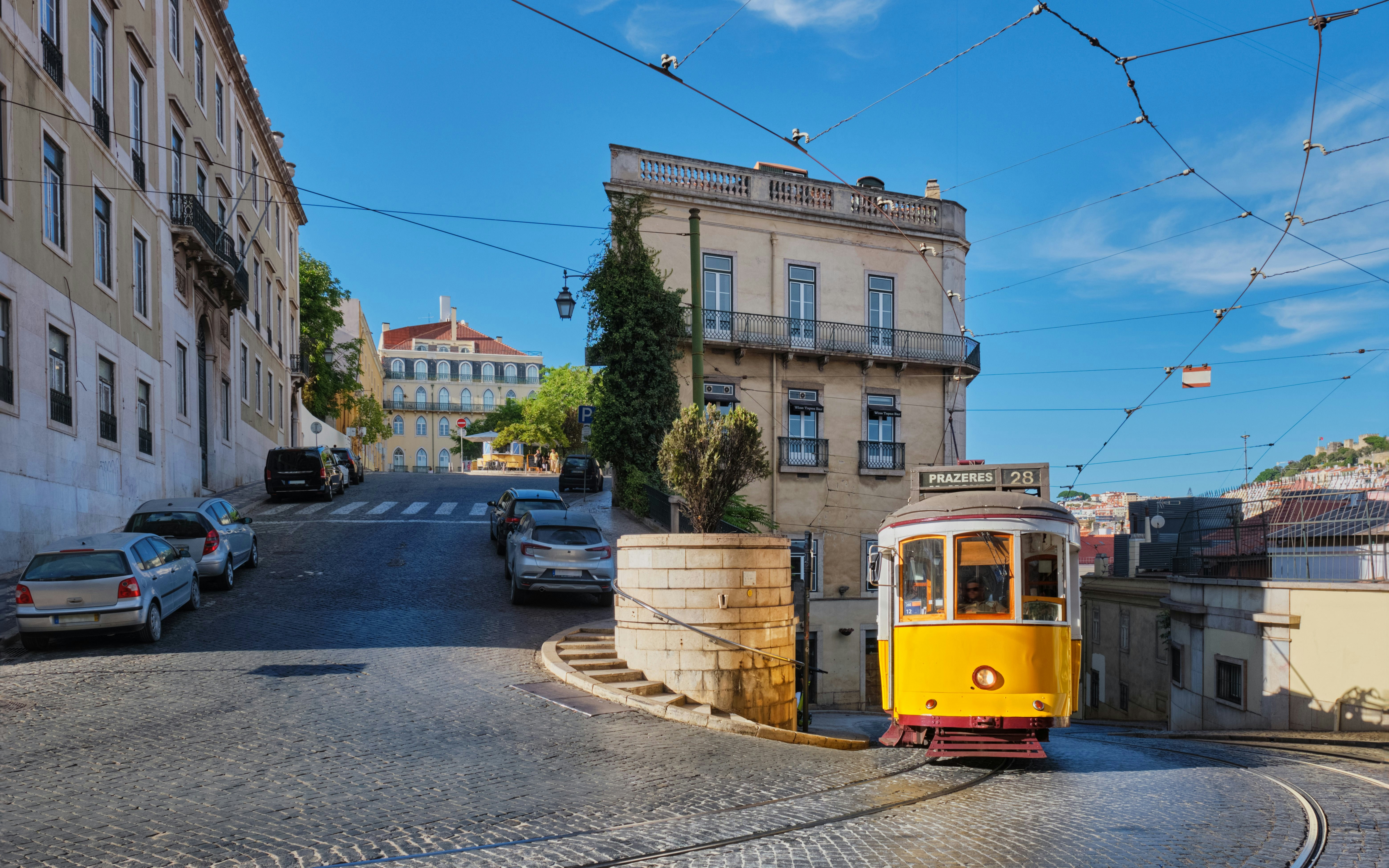 Tram navigating narrow cobblestone streets in Alfama district, Lisbon, Portugal.