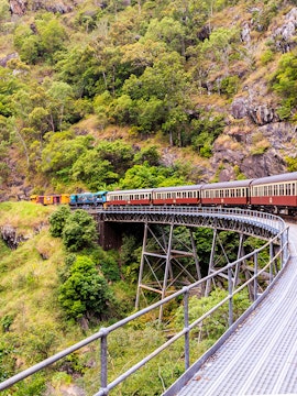 Kuranda Scenic Railway crossing a bridge in lush Cairns rainforest.