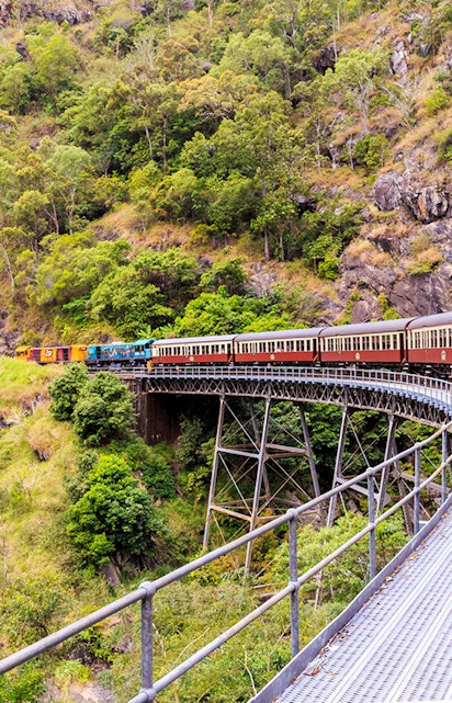 Kuranda Scenic Railway crossing a bridge in lush Cairns rainforest.