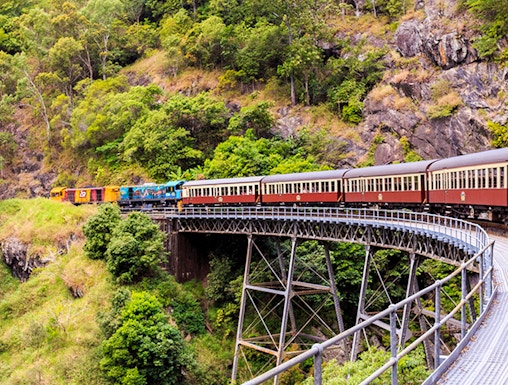 Kuranda Scenic Railway crossing a bridge in lush Cairns rainforest.