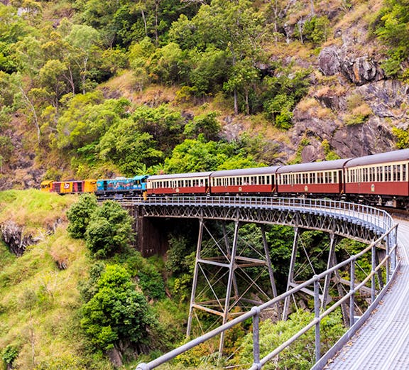 Kuranda Scenic Railway crossing a bridge in lush Cairns rainforest.