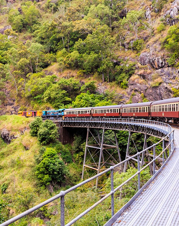 Kuranda Scenic Railway crossing a bridge in lush Cairns rainforest.