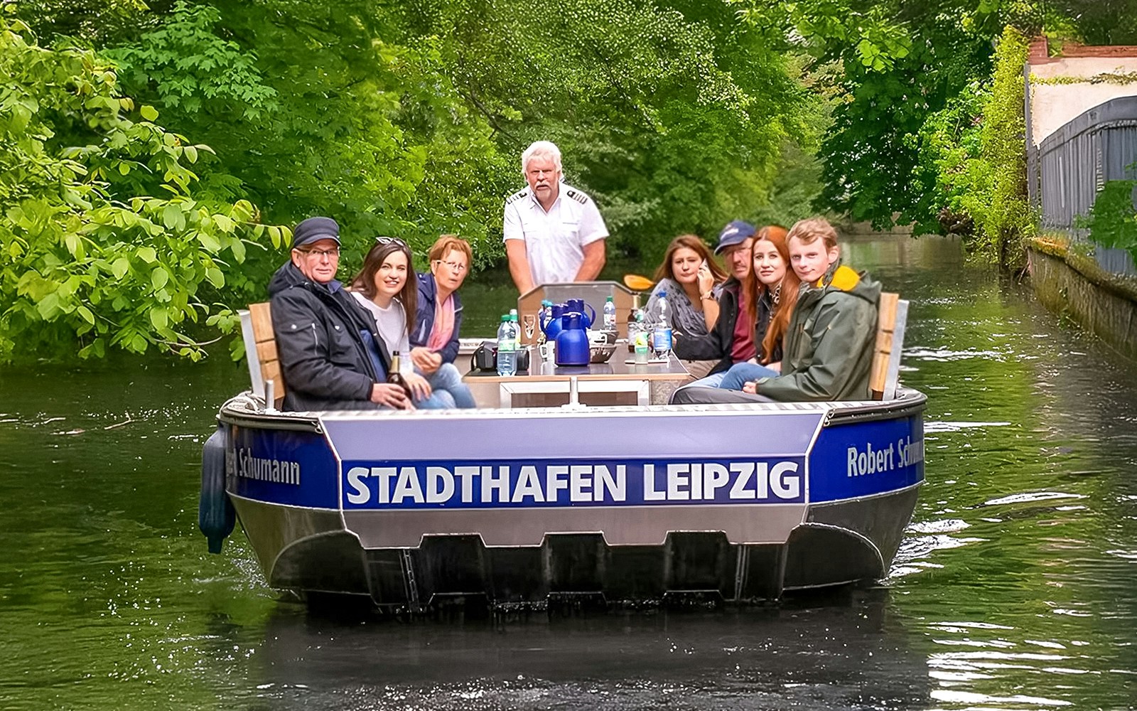 Guests on motorboat tour navigating Auwald forest waterways in Leipzig.
