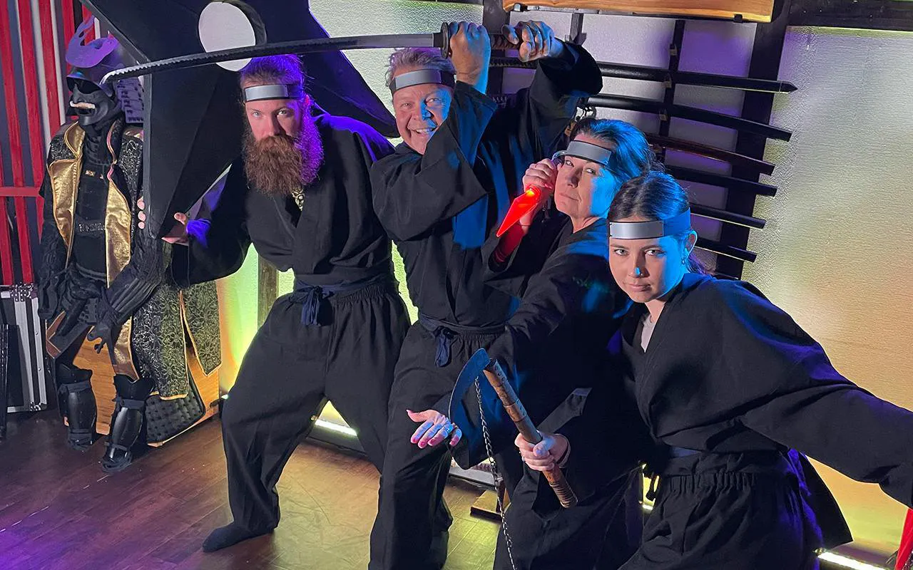 Participants in ninja attire practicing sword skills at Osaka Ninja Workshop.