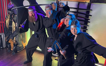 Participants in ninja attire practicing sword skills at Osaka Ninja Workshop.