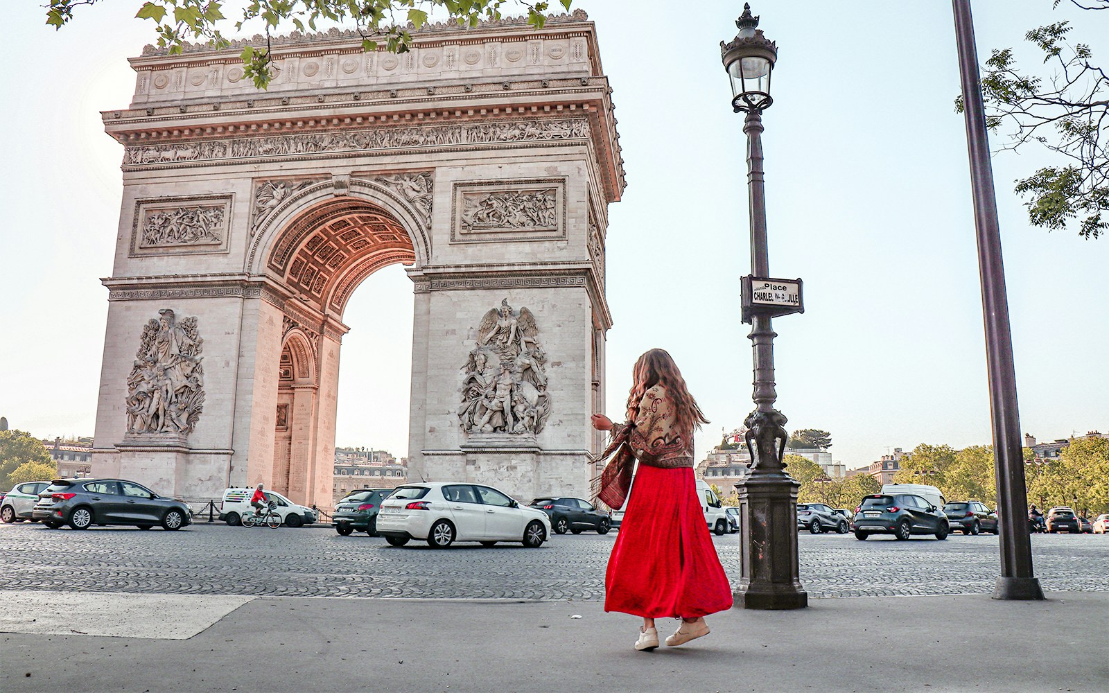Arc de Triomphe with a person walking nearby on a Paris street.