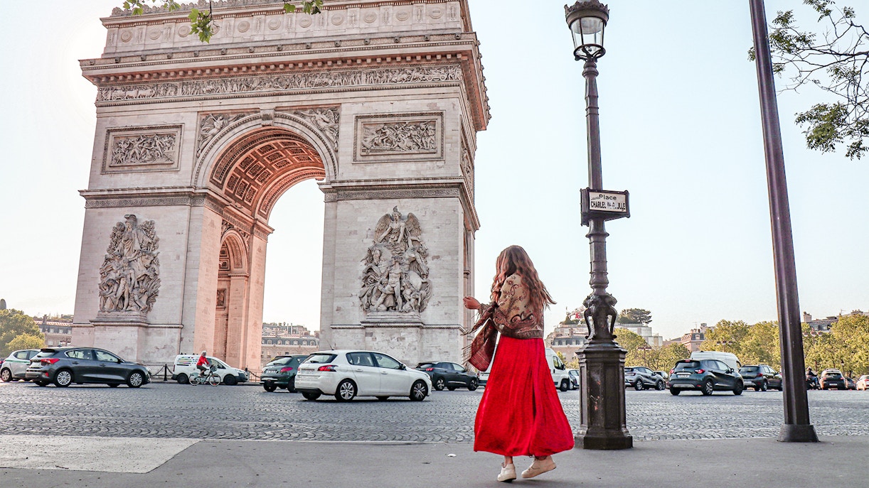 Arc de Triomphe with a person walking nearby on a Paris street.