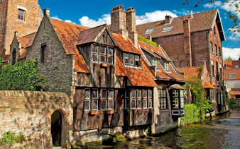 Historic brick buildings along a canal in Bruges, Belgium.