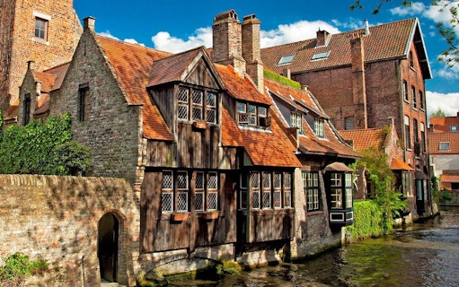 Historic brick buildings along a canal in Bruges, Belgium.