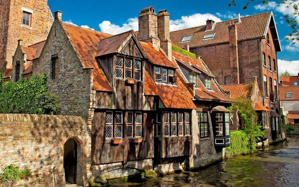Historic brick buildings along a canal in Bruges, Belgium.
