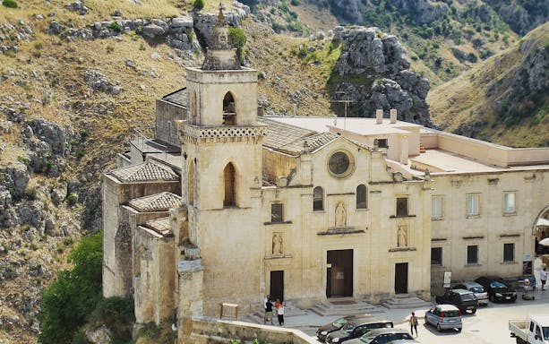 Historic church facade in Matera, Italy, with surrounding rocky landscape.
