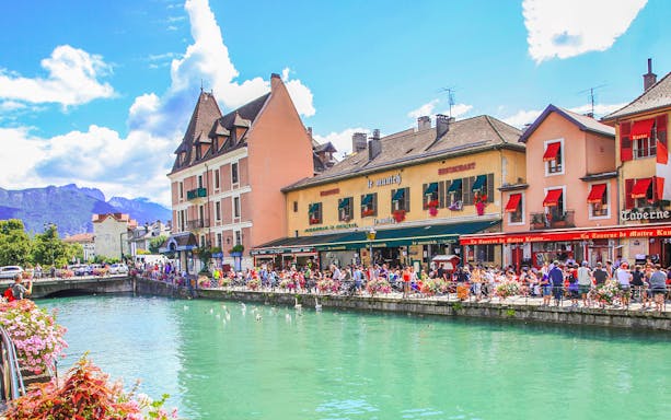 Canal in Annecy with colorful buildings and people enjoying the waterfront.