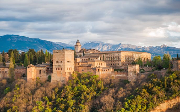Alhambra and Nasrid Palaces in Granada with mountain backdrop.