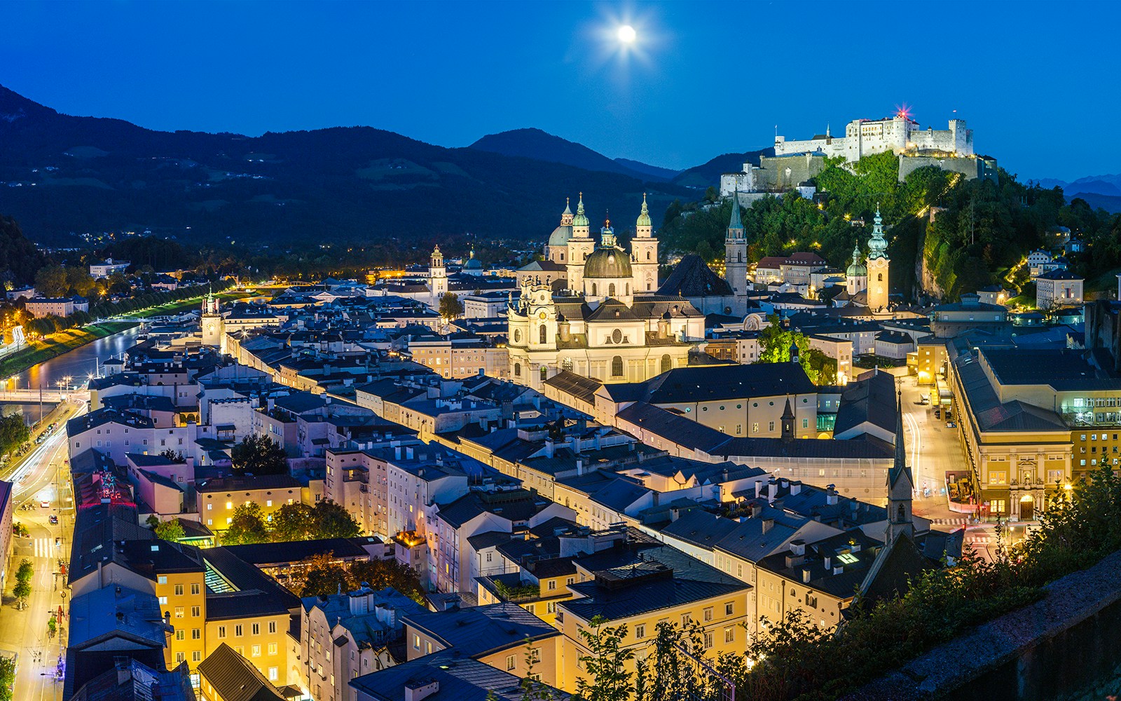Old Town Salzburg at night with Hohensalzburg Fortress illuminated.