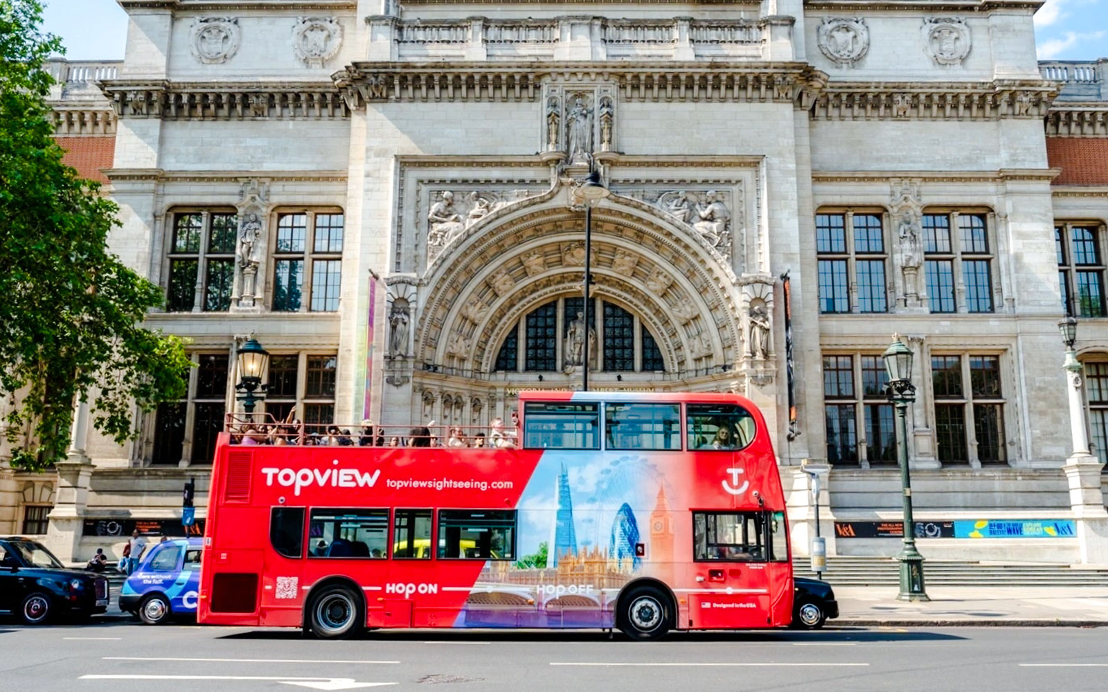 Red Topview hop-on hop-off bus in front of the Victoria and Albert Museum, London.