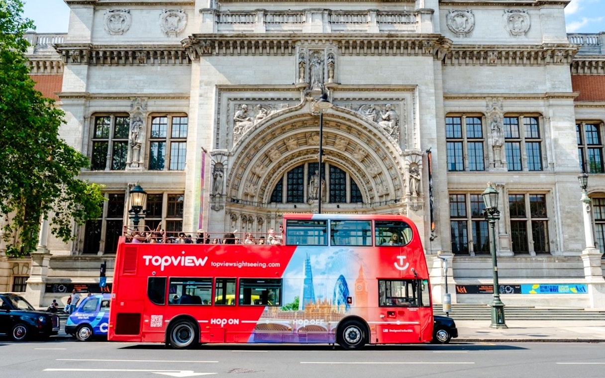Red Topview hop-on hop-off bus in front of the Victoria and Albert Museum, London.