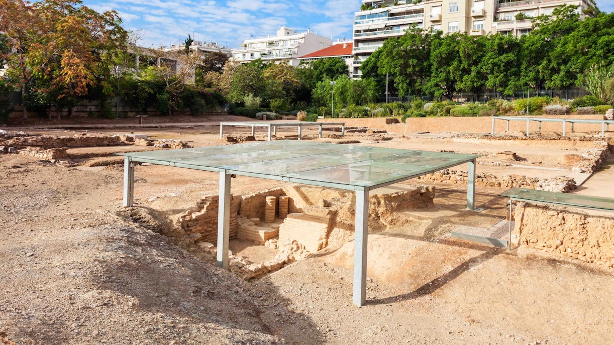 Aristotle's Lyceum ruins in Athens, Greece, surrounded by lush greenery.