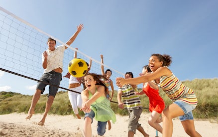 Teenage friends playing volleyball on Moreton Island beach.