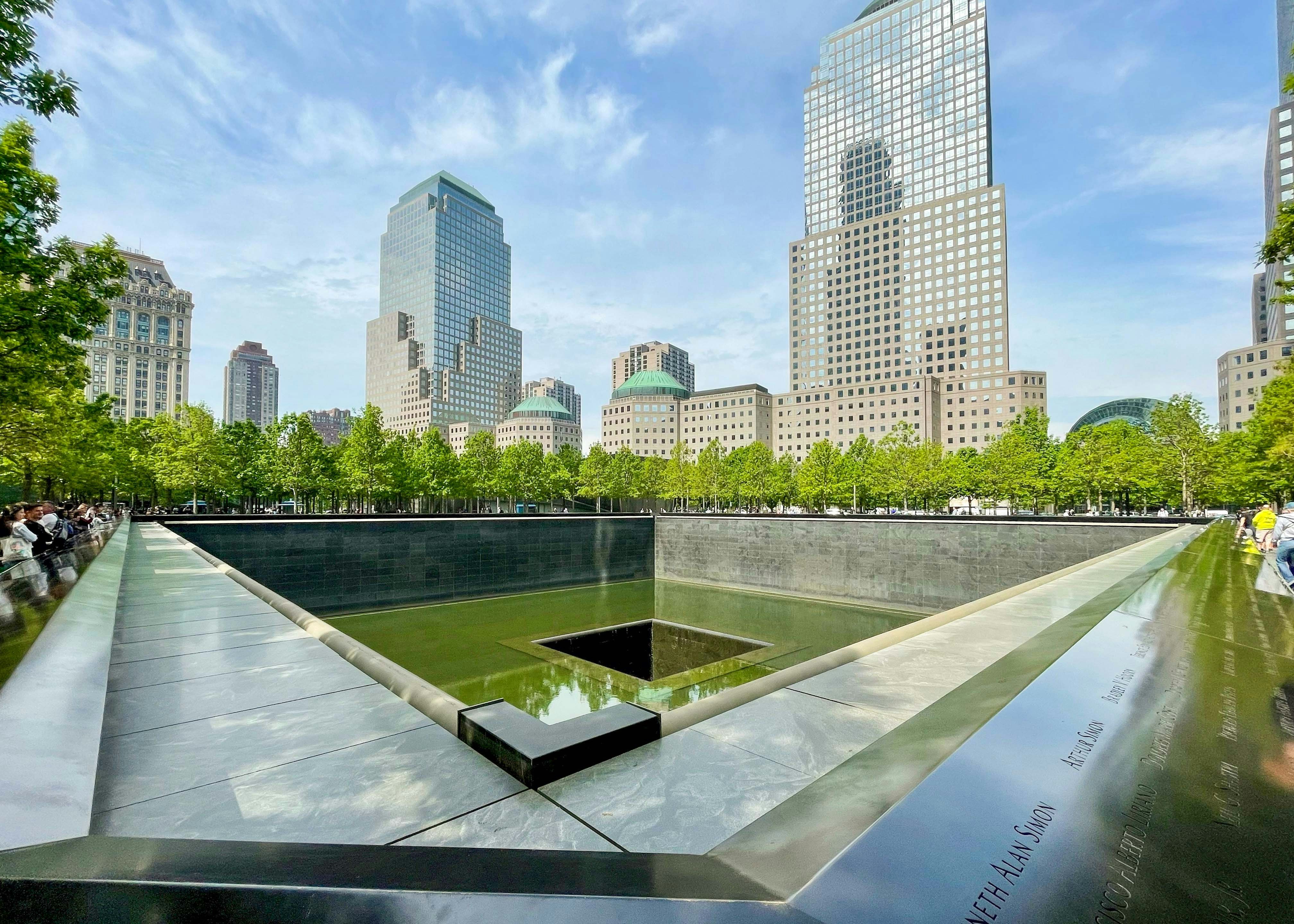 9/11 Memorial reflecting pool with surrounding skyscrapers in New York City.