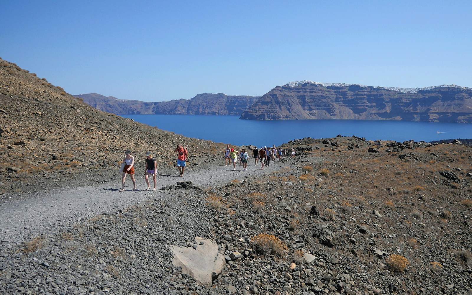 Guests hiking on volcanic terrain during Santorini cruise tour, Greece.