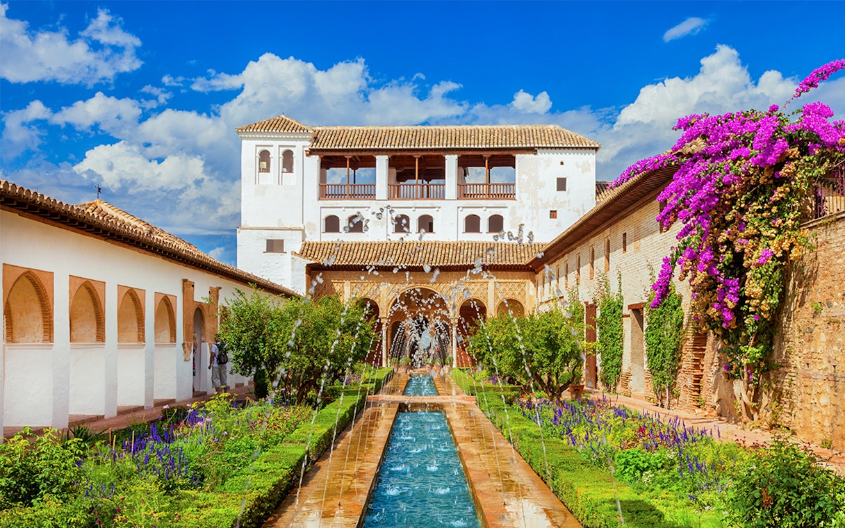Alhambra's Generalife gardens with fountains and vibrant flowers, Granada, Spain.
