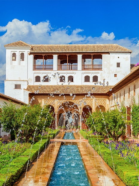 Alhambra's Generalife gardens with fountains and vibrant flowers, Granada, Spain.
