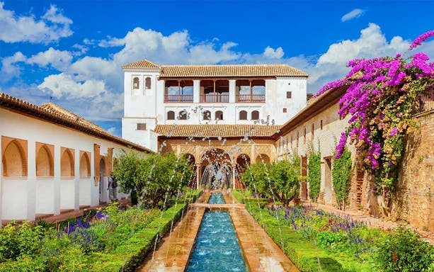 Alhambra's Generalife gardens with fountains and vibrant flowers, Granada, Spain.