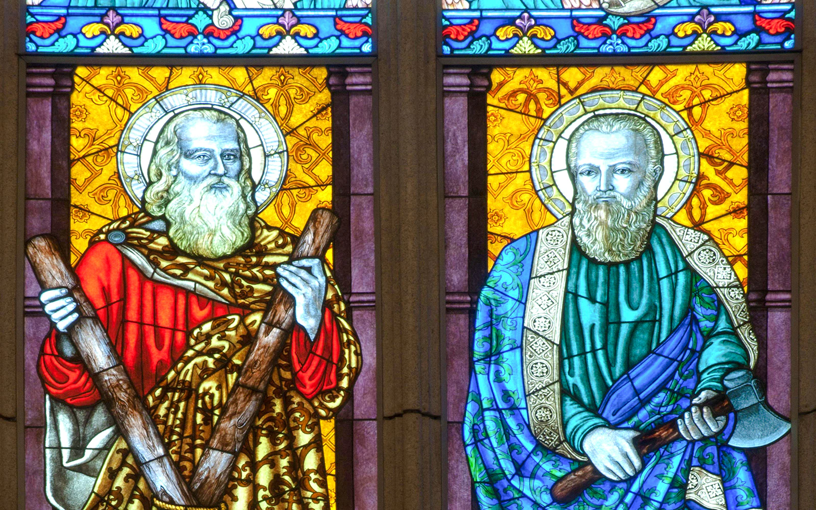 Stained glass window depicting two saints holding wooden staffs at St. Matthias Church.