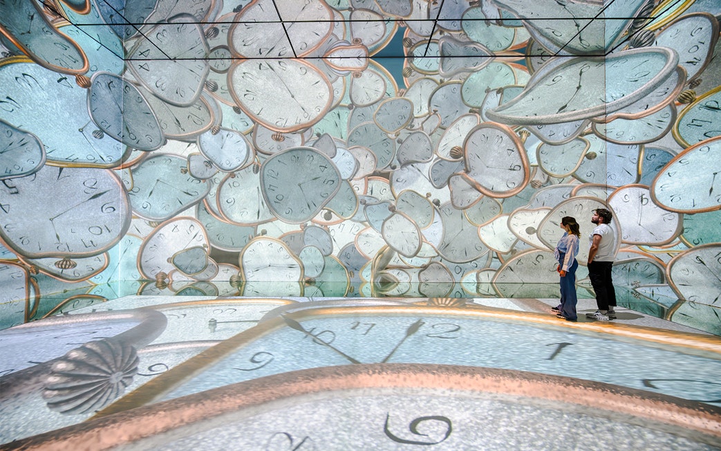 Visitors exploring melting clock projections at Frameless London immersive art exhibit.