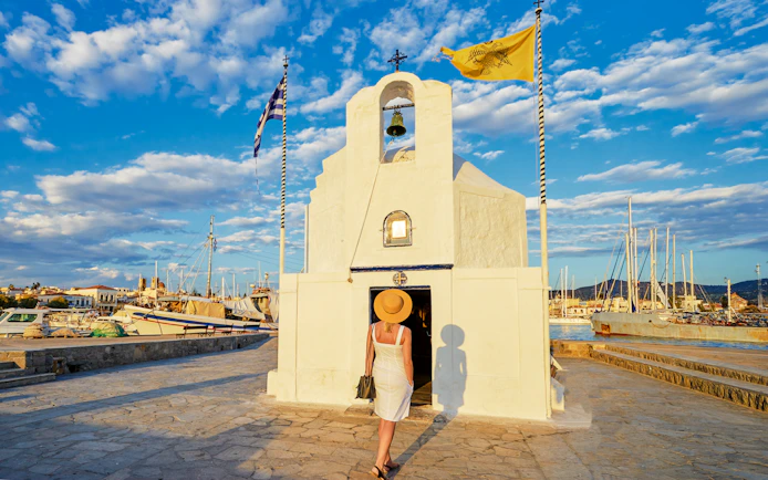 Agios Nikolaos church at Aegina port, Greece, with boats and blue sky.