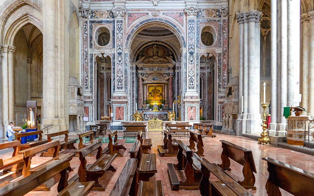 San Lorenzo Maggiore interior with ornate altar and wooden pews.