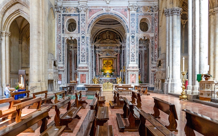 San Lorenzo Maggiore interior with ornate altar and wooden pews.