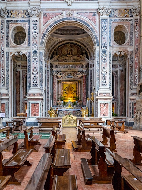San Lorenzo Maggiore interior with ornate altar and wooden pews.