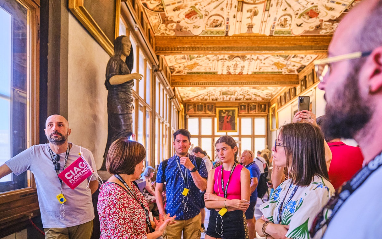 Small group tour in the Vasari Corridor, Florence, with guide explaining artwork.