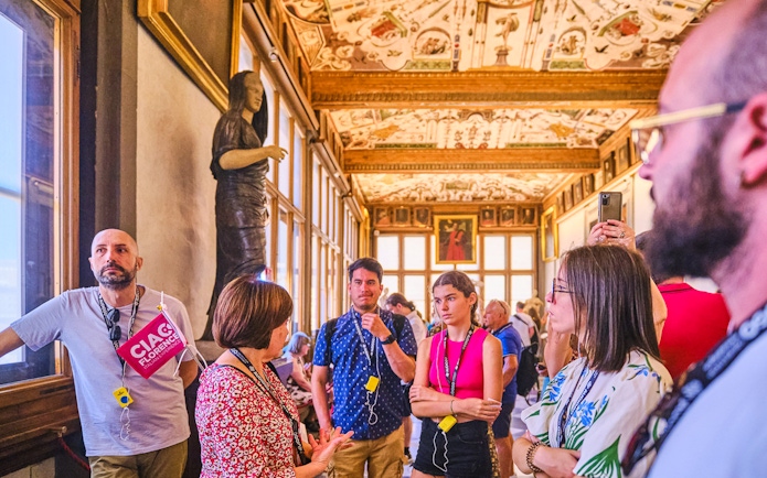 Small group tour in the Vasari Corridor, Florence, with guide explaining artwork.