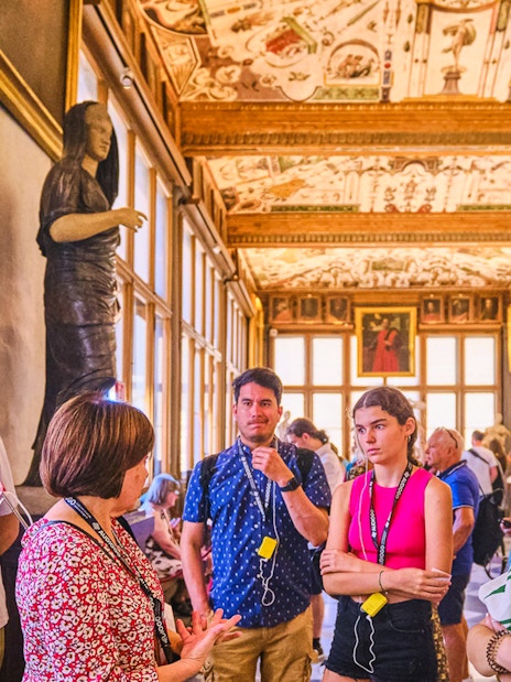 Small group tour in the Vasari Corridor, Florence, with guide explaining artwork.