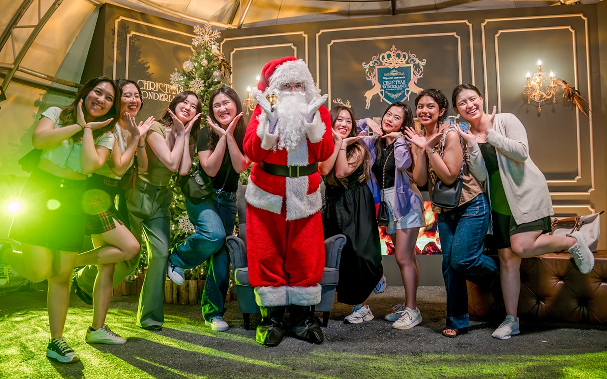 Santa Claus posing with visitors at Gardens by the Bay Christmas event.