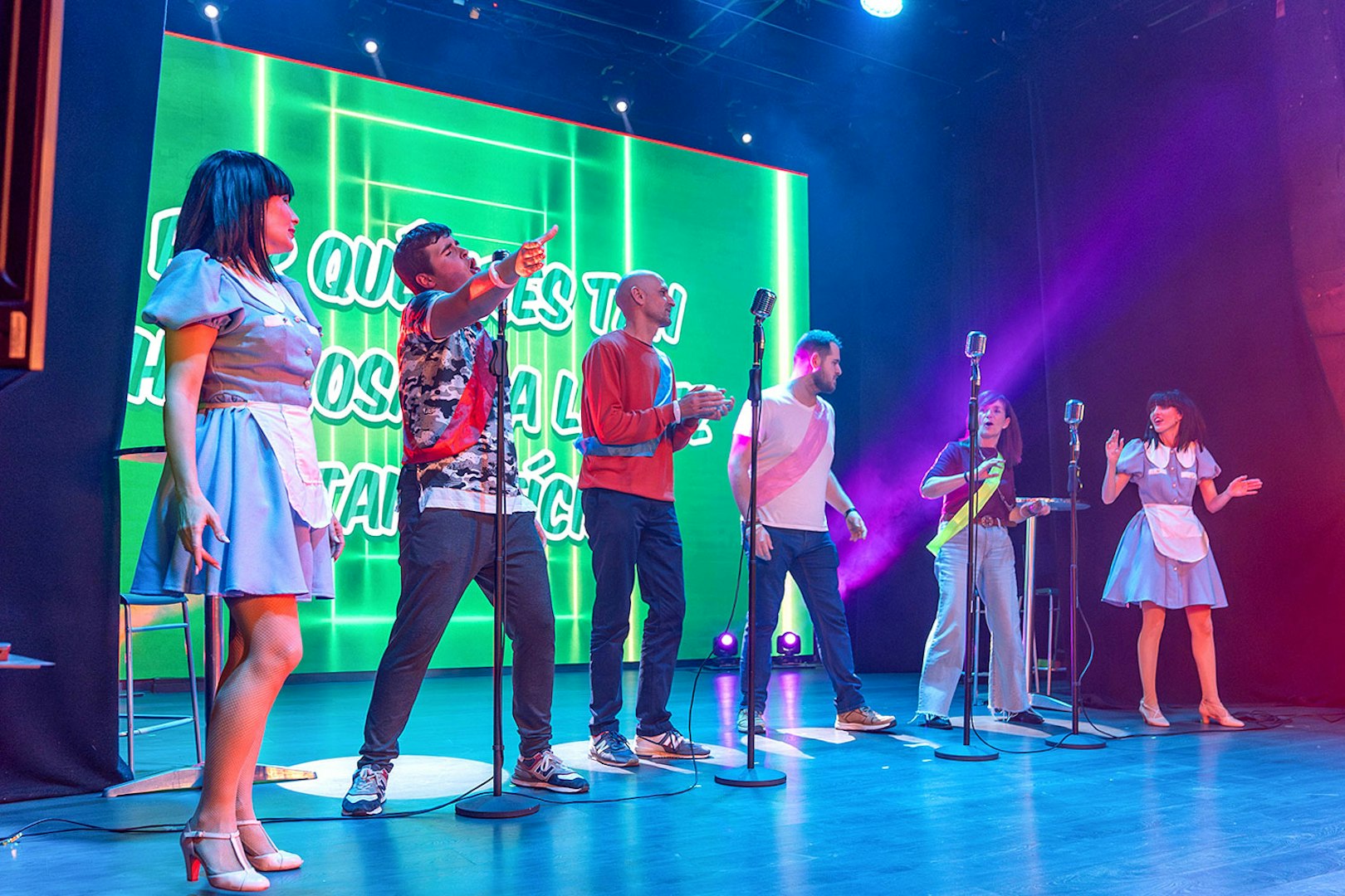Performers on stage during "Coctel, un Musical al reves" with vibrant green backdrop.